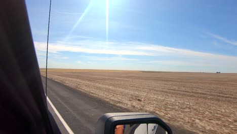 pov fuera de la ventana del lado del pasajero mientras conduce por campos de trigo cosechados en una zona agrícola del estado de washington oriental