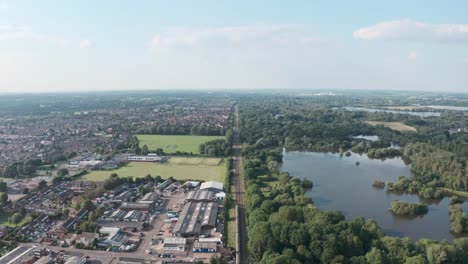 Follow-drone-shot-over-British-rail-train-along-long-straight-track-in-the-countryside