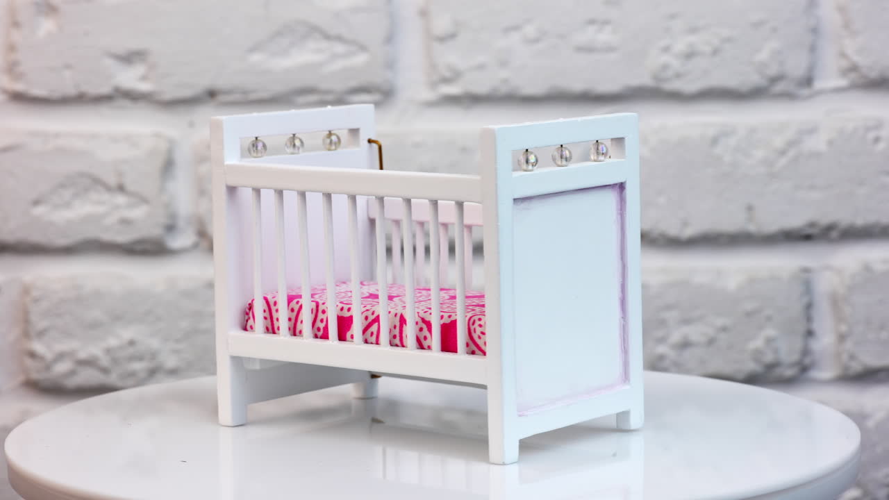 Piccolo letto giocattolo bianco per bambola. Interno di camera da letto bianca in miniatura.