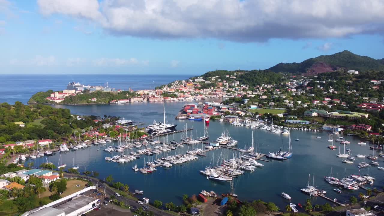 Aerial fly away from picturesque harbour with boats, houses on hills