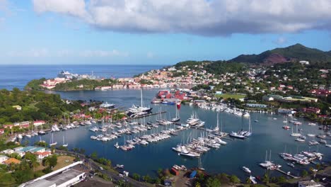 aerial fly away from picturesque harbour with boats, houses on hills