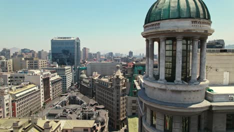 Aerial-revealing-shot-of-Ariztía-Building,-Historic-Skyscraper-in-Santiago-cityscape,-Chile