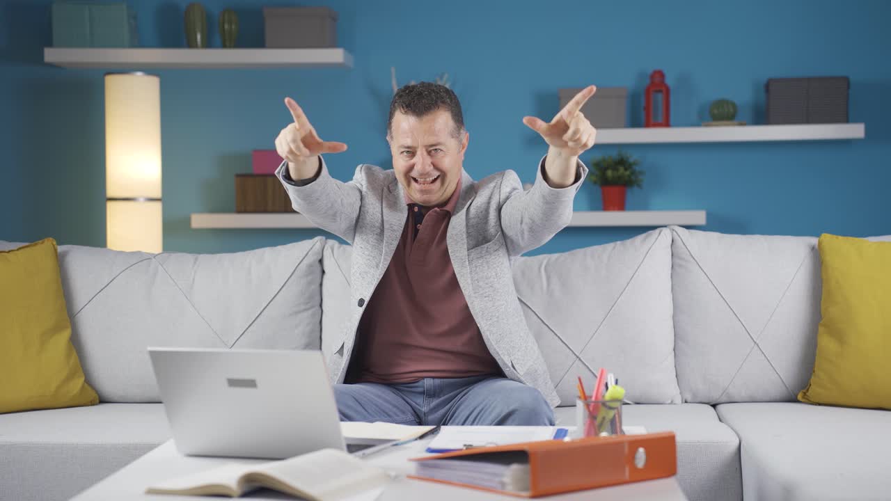 el hombre que trabaja en la oficina hace el símbolo del corazón mirando a la cámara.