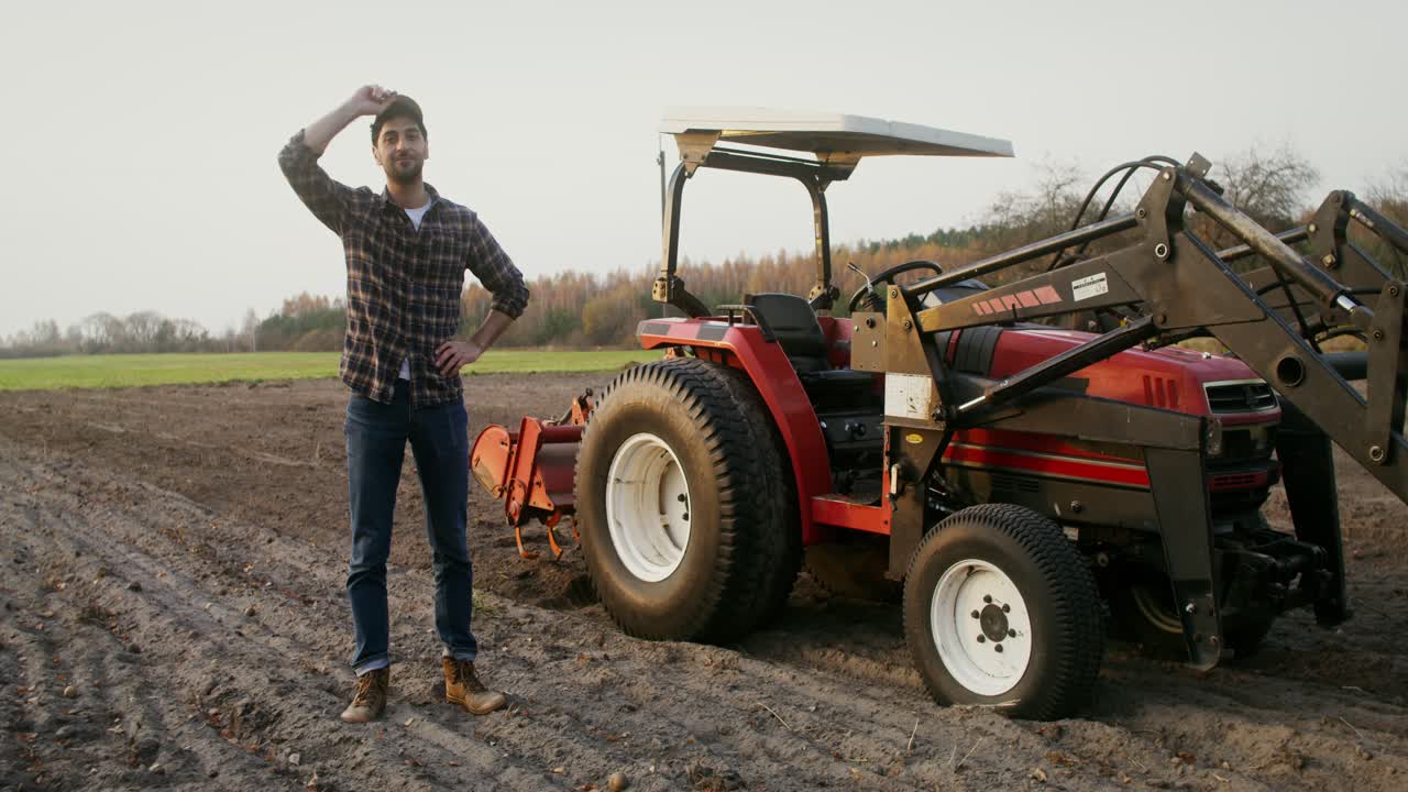 agricultor de pie al lado del tractor en el campo