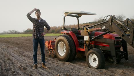 farmer standing beside tractor in field