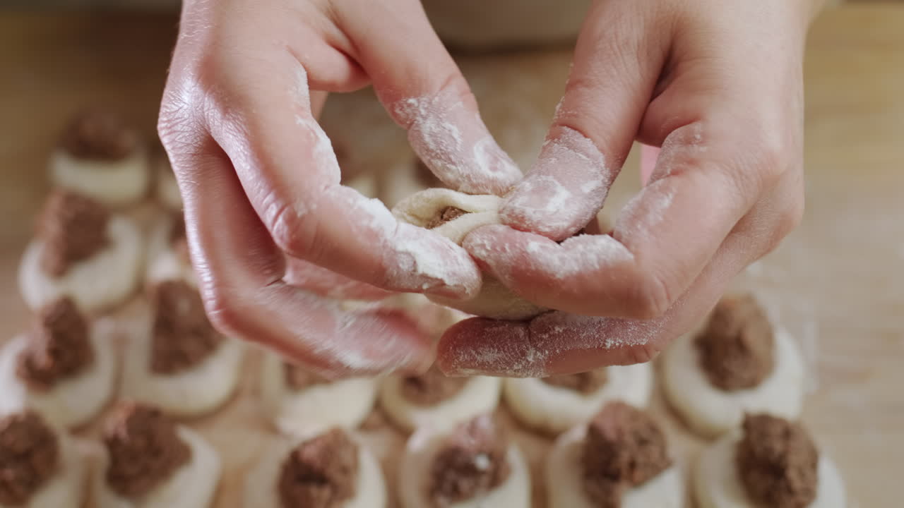 Baker's hands sculpt dumplings with meat filling