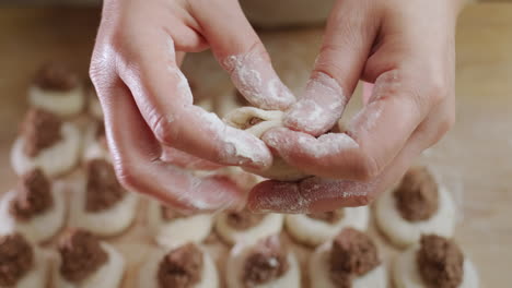 baker's hands sculpt dumplings with meat filling