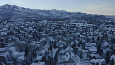 beautiful aerial drone shot taking houses and roads covered with snow over park city, utah,usa in a cold wintry evening