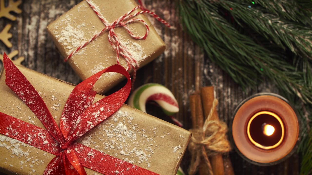 Mano che posiziona un regalo di Natale su un tavolo di legno con decorazioni festive.