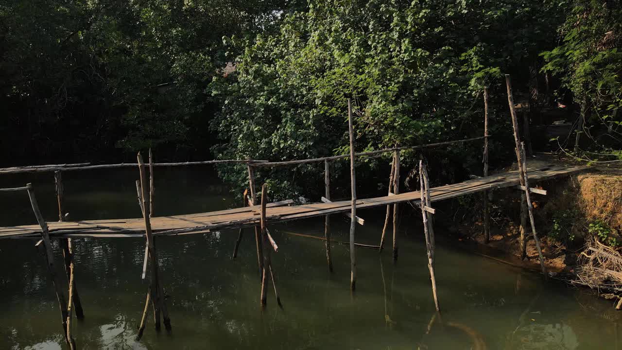 toma aérea de primer plano lento de un puente de madera sobre un río en la isla tropical de koh chang, tailandia