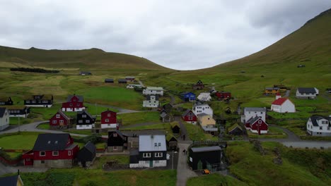 drone taking off reveals the village of mikladalur and its green environment