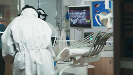 orthodontist in coverall using tablet explaining dental x ray