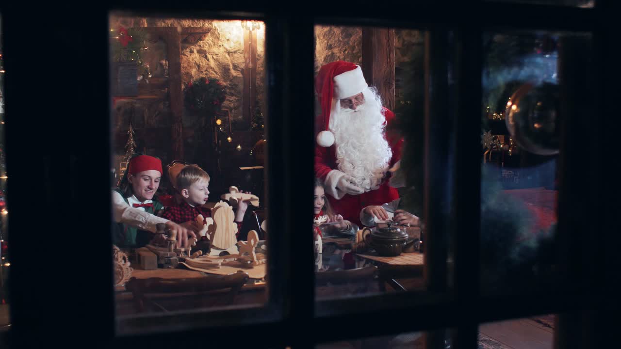 Santa Claus residence outside view through the window. Santa Claus and children with elves make out gifts