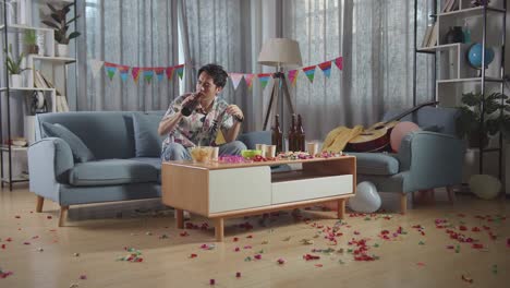 man drinking alone at a messy party