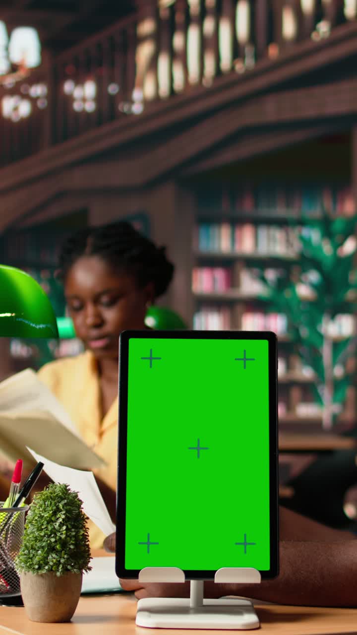Mockup Tablet Layar Hijau Vertikal di Perpustakaan dengan Mahasiswa Belajar