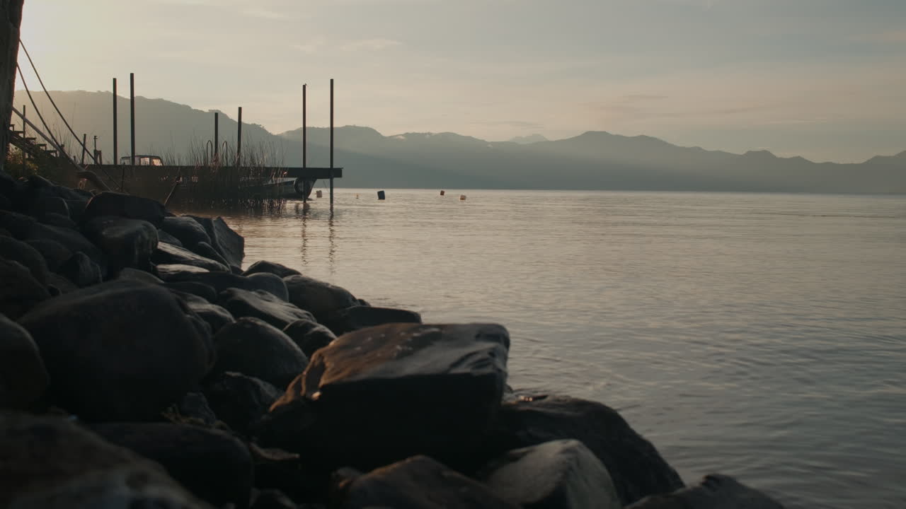 Wide Establishing Shot of Epic Sunrise Over Beautiful Calm Lake, Black Stones, Still Water, Lake Atitlan, Guatemala