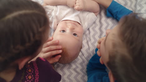 brother and sister looking at cute baby on bed. siblings love concept