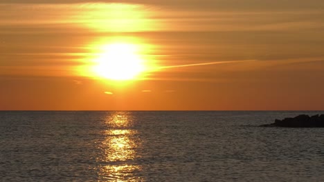 time lapse hazy orange sunrise over calm silver sea, mediterranean coast