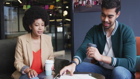 diverse business people sitting going through paperwork drinking coffee in a modern office