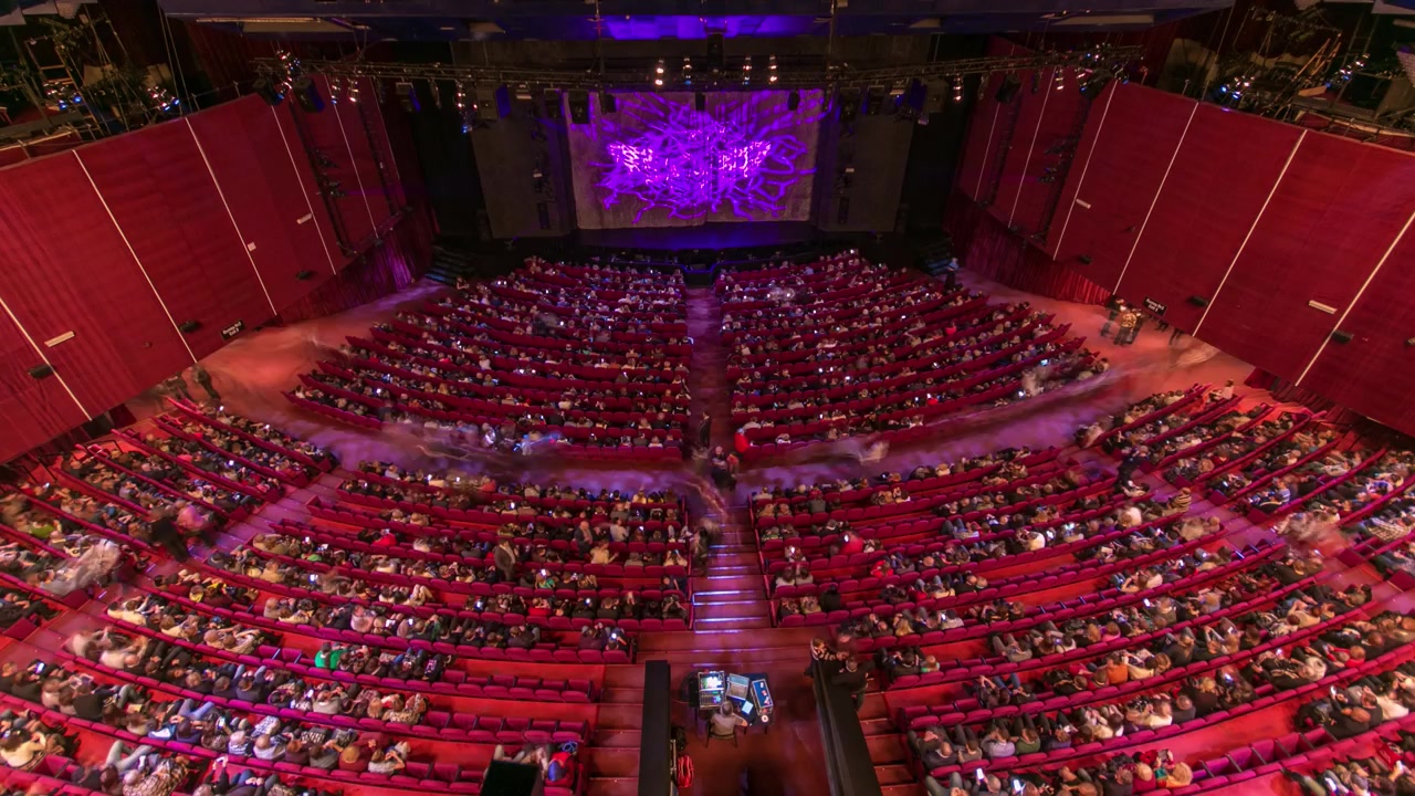 Spettatori si radunano nell'auditorium e guardano lo spettacolo a teatro, timelapse. Grande sala con poltrone rosse. Spettatori che riempiono i posti fino allo spegnimento delle luci. Vista dall'alto.