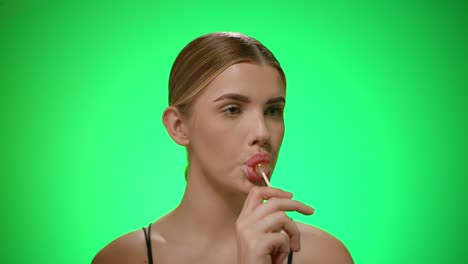 side portrait view woman licks a tasty colorful lollipop, studio shot