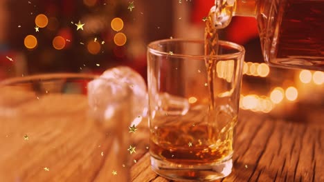 animation of glowing stars falling over glass of brandy and christmas tree