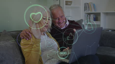 animación de iconos de los medios sobre una pareja caucásica mayor usando una computadora portátil