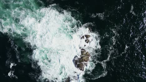 Topdown-view-Ocean-waves-breaking-into-submerged-rocks,-Galiza-Coastline,-Deep-blue-Water