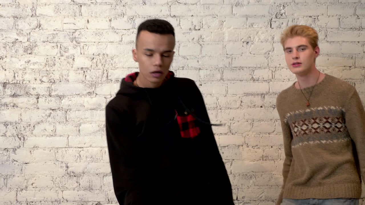 아프리카 남자가 그의 미국 친구와 함께 춤을 추고, 배경에  벽돌 벽. 디스코, 춤, 운동, 에너지, 청소년 개념.