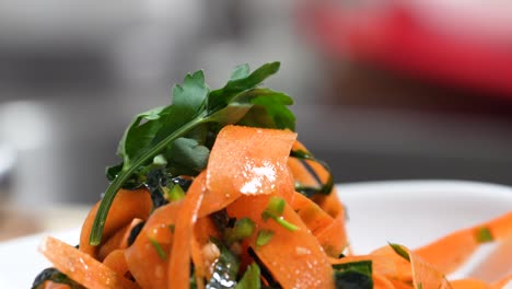guarnición de perejil fresco encima de fideos de pasta naranja coloreados o infundidos con pasta de tomate, zanahorias o garbanzos por el chef para el almuerzo o la cena, cierre de manos en restaurante o cocina casera