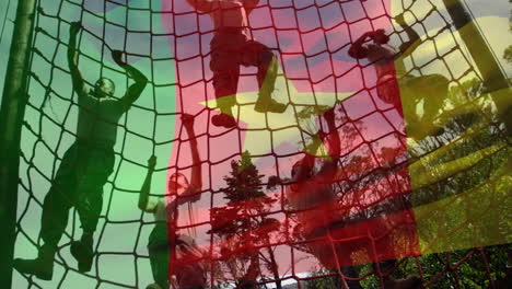 ondeando la bandera de camerún contra los soldados masculinos que suben a la red durante una carrera de obstáculos en el campamento de entrenamiento