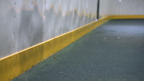 subtle reflection of person on metallic wall with dynamic soccer ball impact captured mid-motion, emphasized by yellow wall border and shadow play, creating energy under bright nighttime lighting