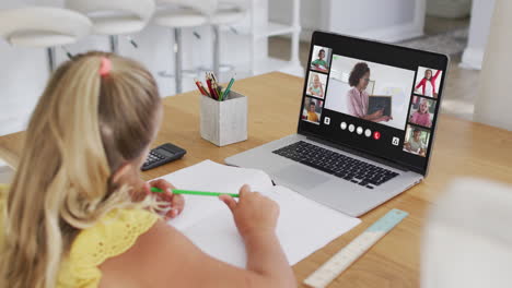 caucasian girl having a video conference with teacher and classmates on laptop at home