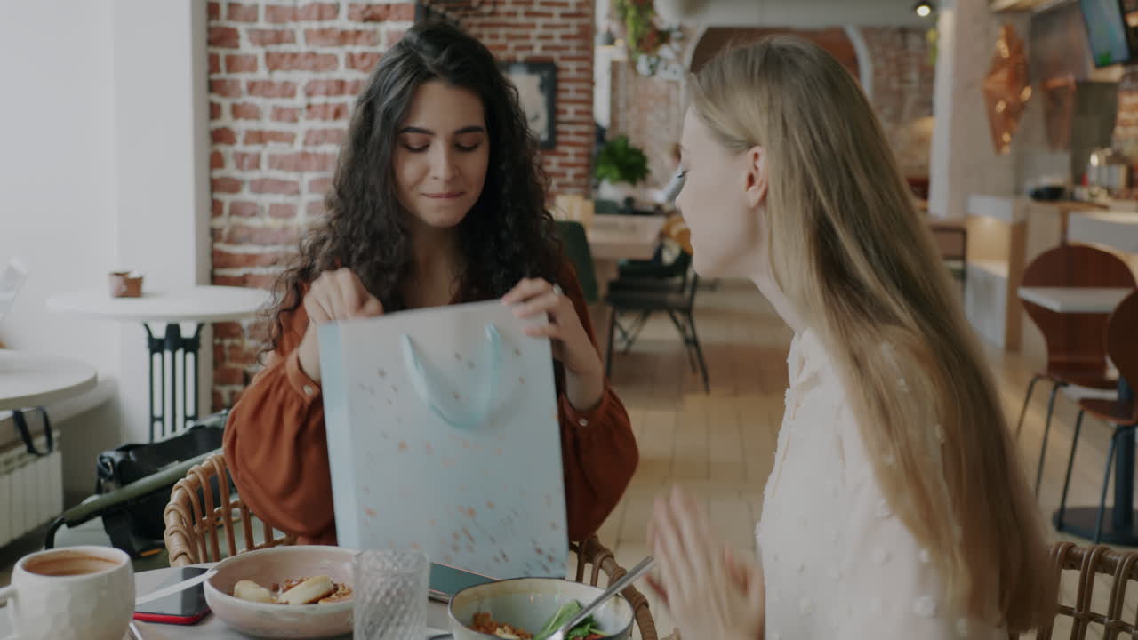 Friends Unboxing a Gift in a Cafe