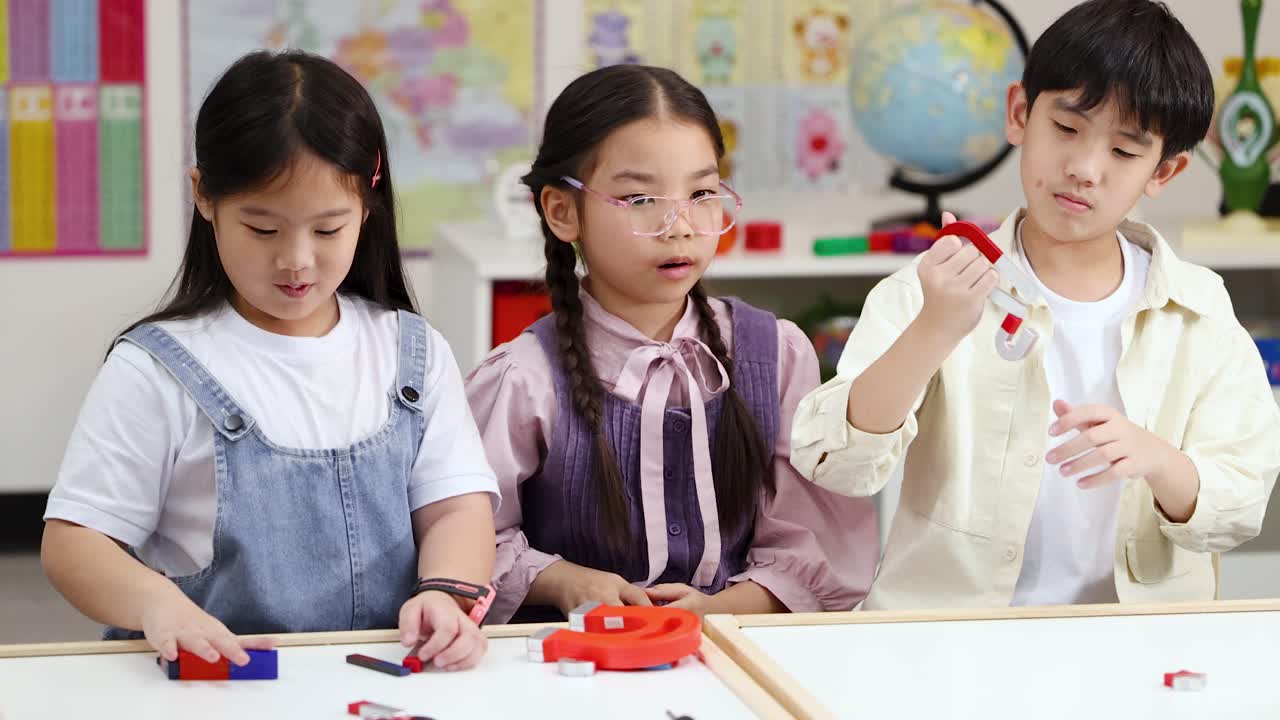 小学校の生徒3人が、教室での実践的な理科の授業で磁石と磁力を探求している様子。