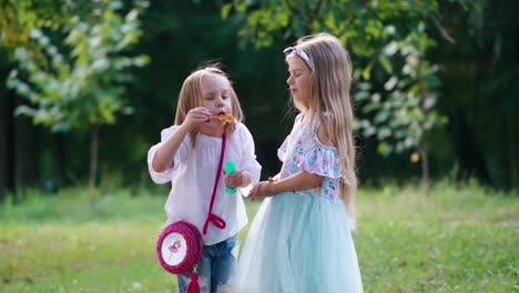 girls blowing bubbles in park. two girls blowing soap bubbles outdoor