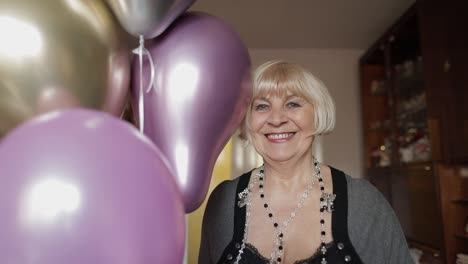 cute grandma celebrates her birthday. holds multicolored balloons in her hands