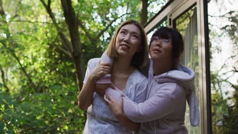 Asian-mother-and-daughter-embracing-in-garden-and-smiling