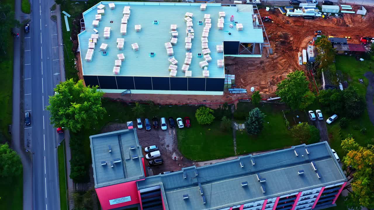 Warehouse or commercial building under construction with stacked materials on roof