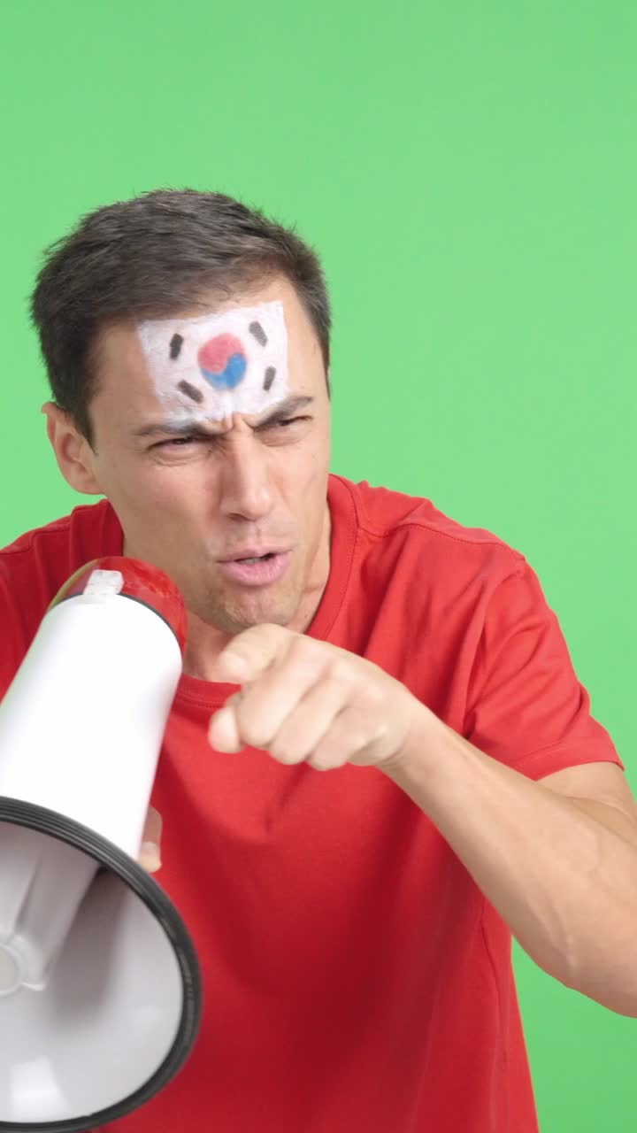Excited man with south korean flag on face using a megaphone