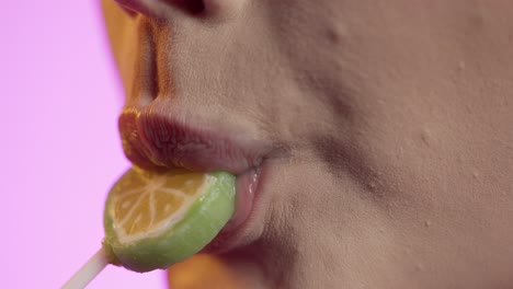 mujer lamiendo helado con su lengua, boca en primer plano en fondo rosa