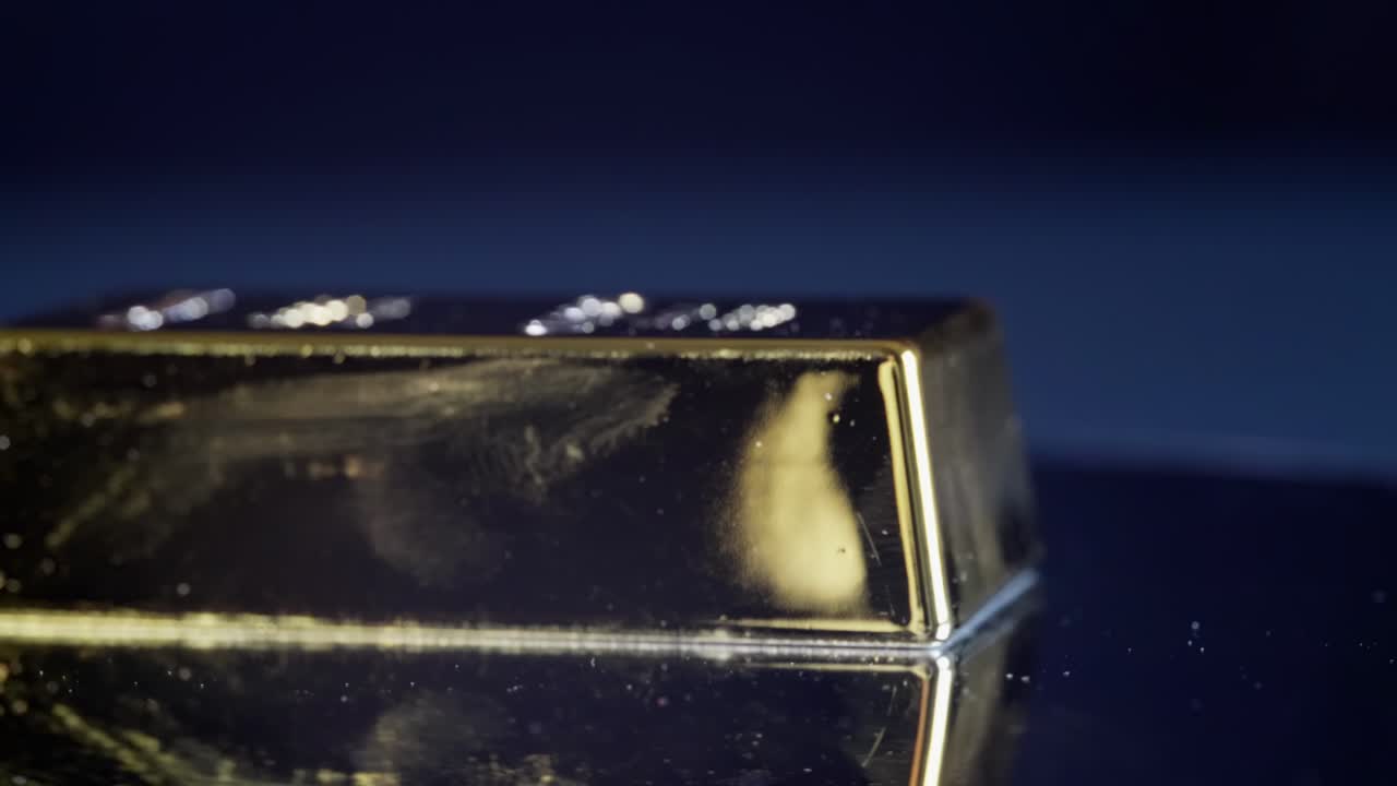 la barra de oro sólido gira en macro de cerca en una superficie reflectante, mostrando el valor del oro puro, el lujo y el significado industrial