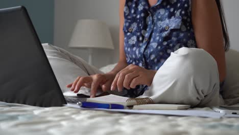 caucasian woman working from home on bed typing on laptop, covid-19