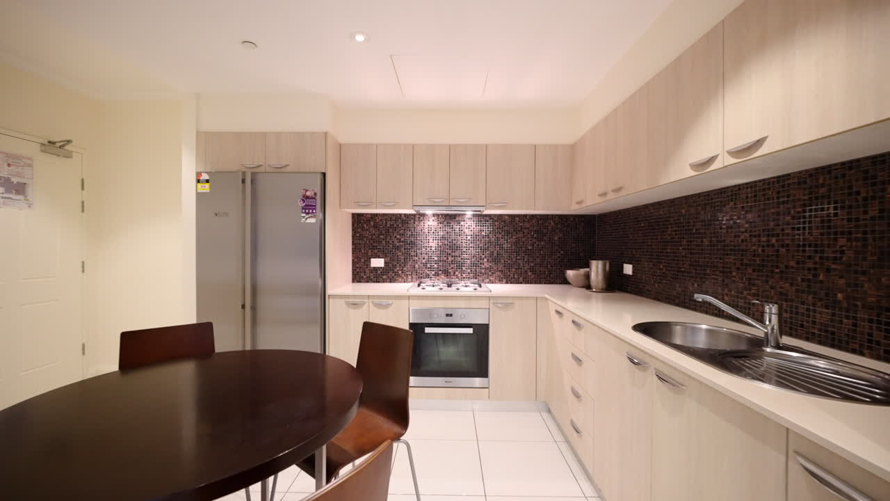 Modern Apartment Kitchen with Brown Tiled Backsplash And Stainless Steel Appliances, Brown Accented Round Dining Table