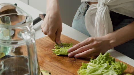 close up of a woman hands mashing avocado with a fork on a wooden chopping board