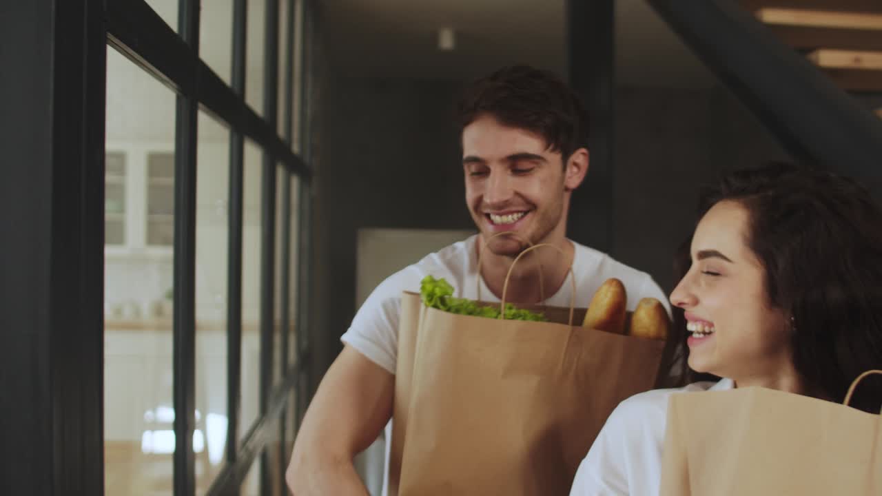 pareja feliz caminando con bolsas de papel con comida saludable. pareja abrazándose en casa