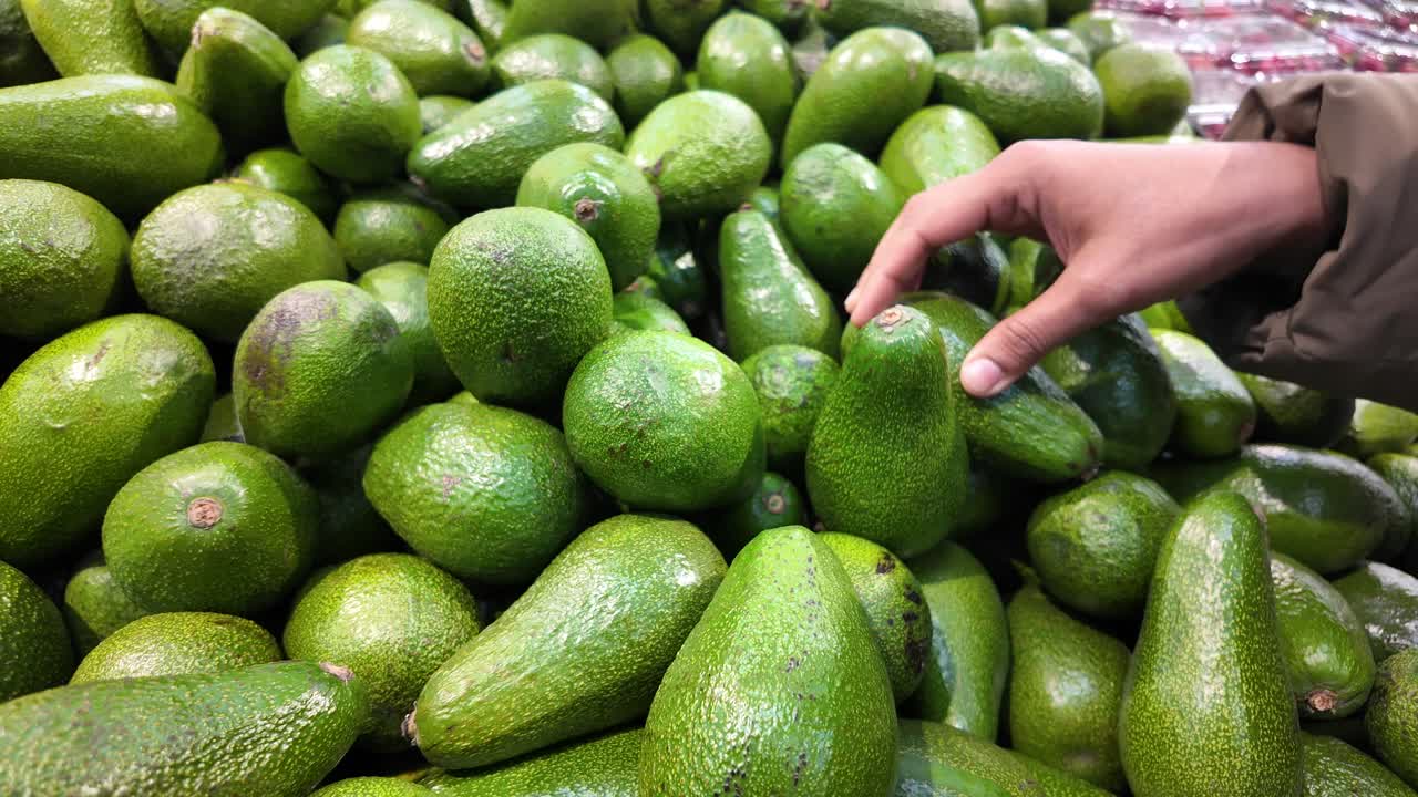 persona seleccionando aguacates en una tienda de comestibles