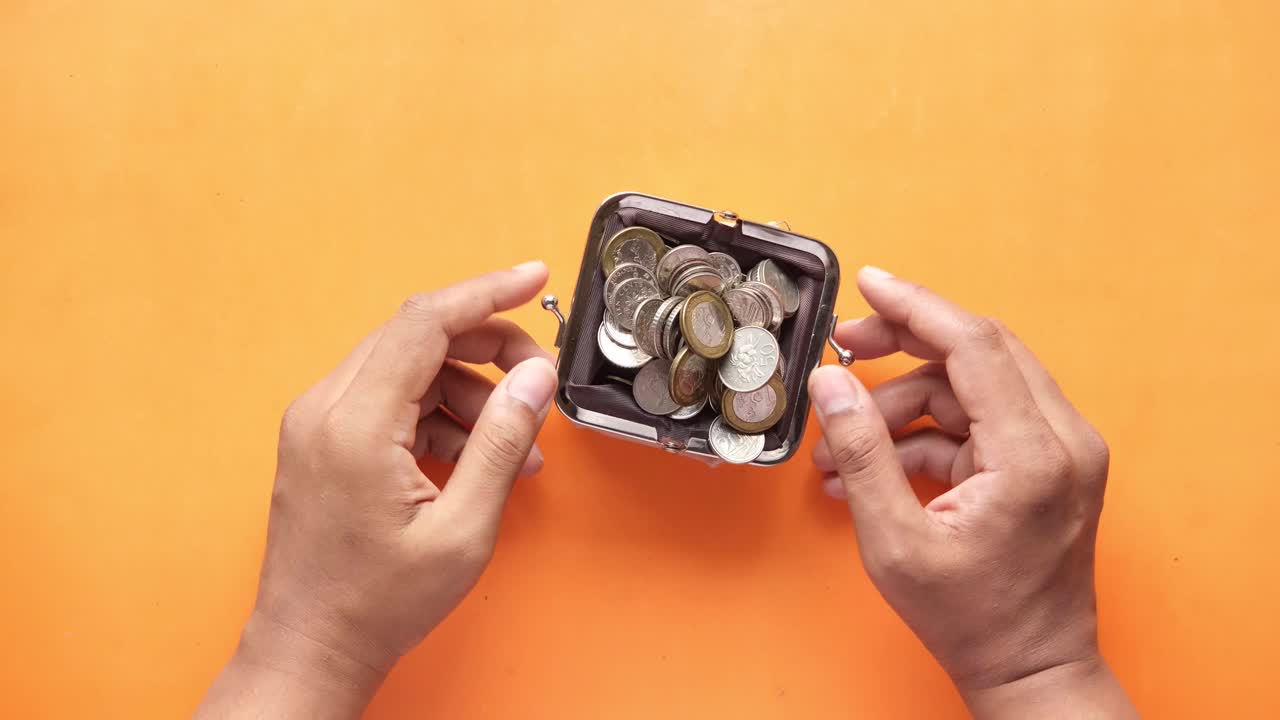 manos sosteniendo una pequeña billetera con monedas