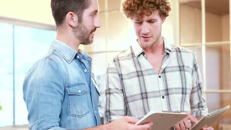 casual businessmen speaking together and holding tablet and clipboard