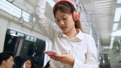 mujer joven usando teléfono móvil en un tren público